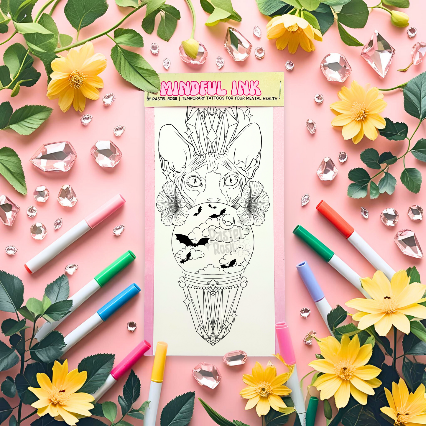Temporary tattoo with cat design surrounded by markers, flowers, and leaves on a pink background