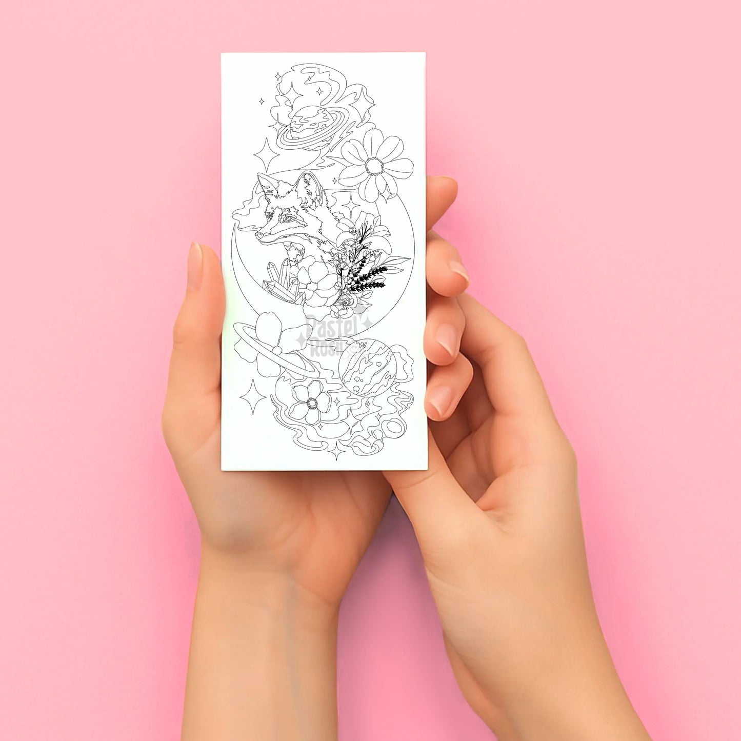 Hands holding a sheet of temporary tattoo designs against a pink background