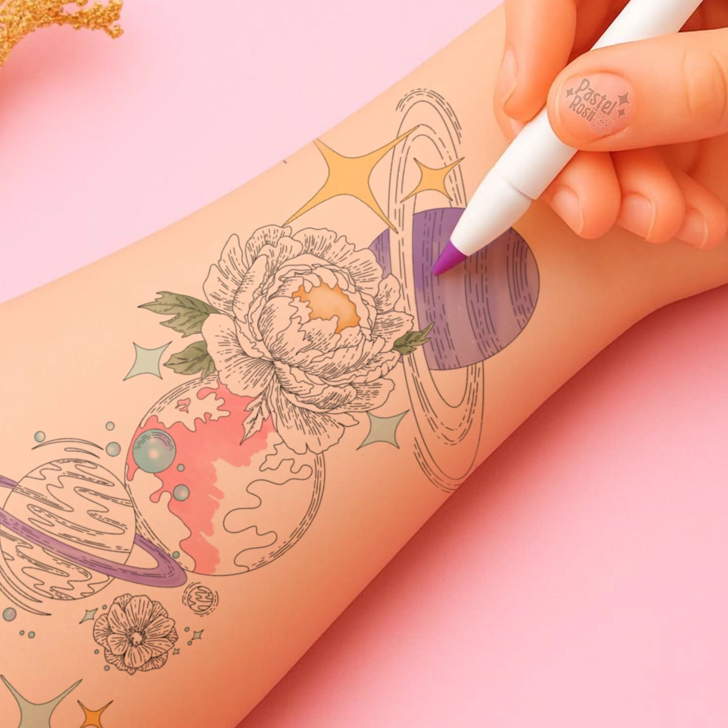Hand with tattoo of celestial designs on a pink background