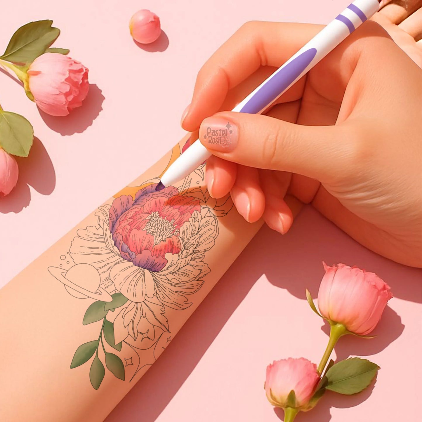 Hand holding a pen with a floral tattoo design on a pink background with flowers.