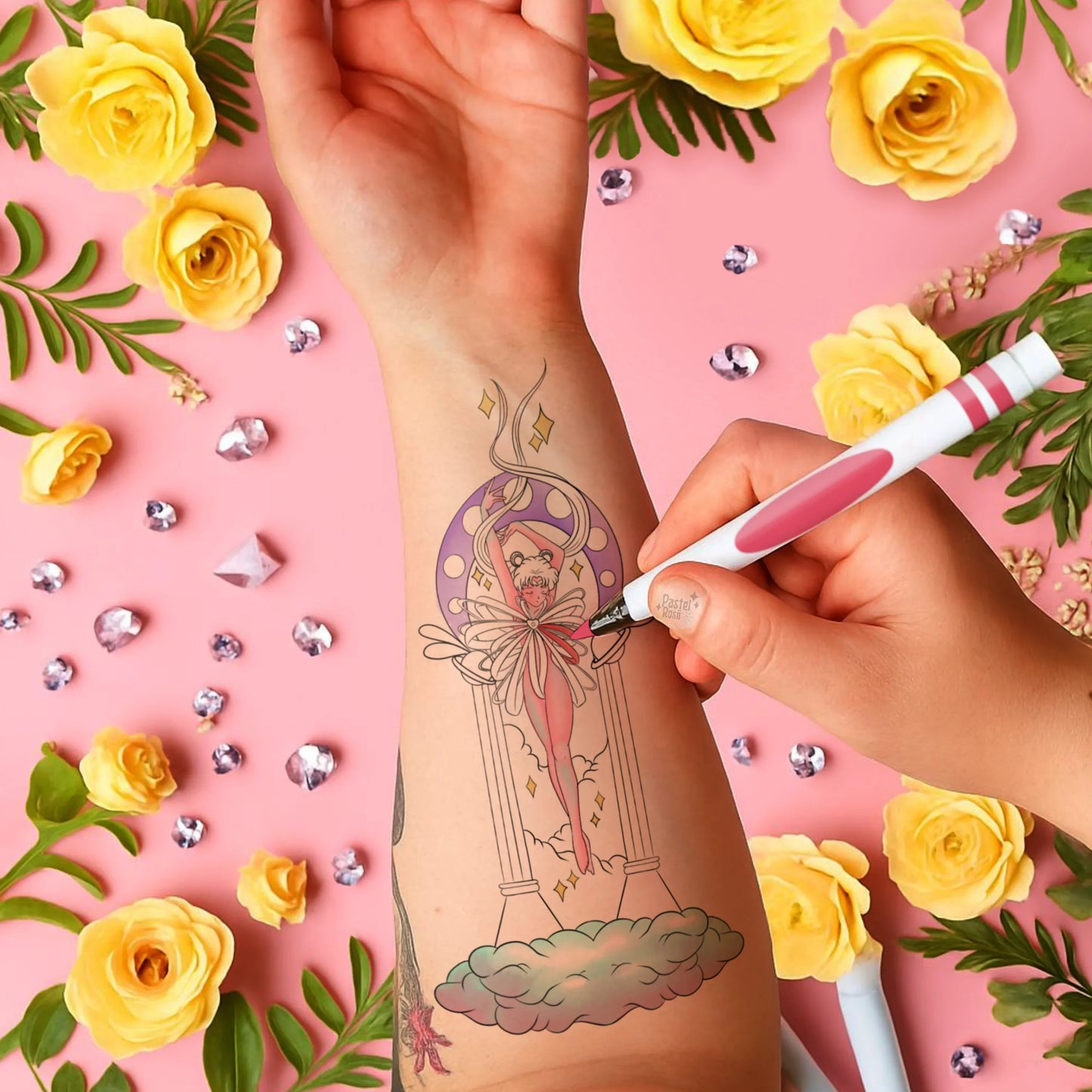 Hand applying a temporary tattoo of a woman design on a pink background with yellow roses and decorative elements.