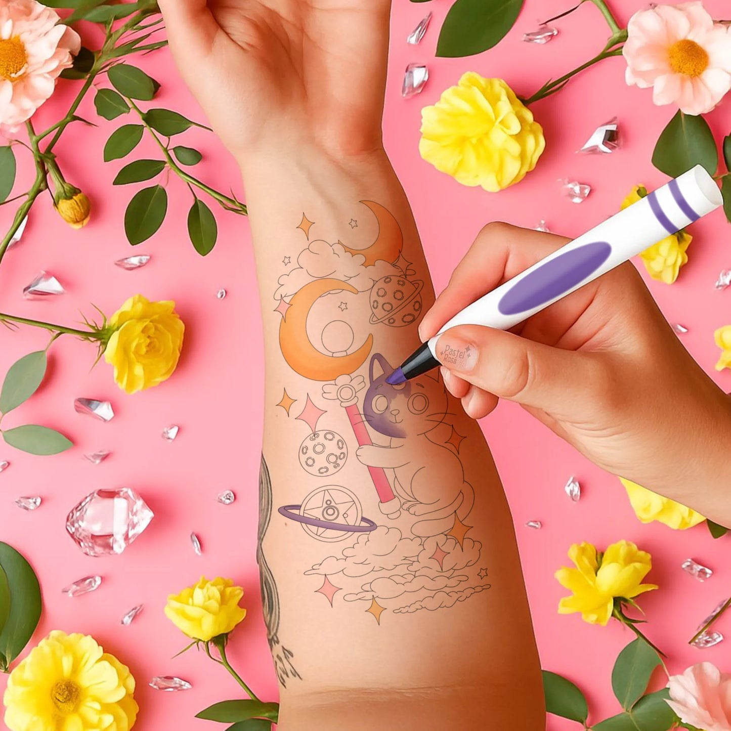 Person getting a temporary tattoo of a space-themed design on a pink background with flowers and crystals.