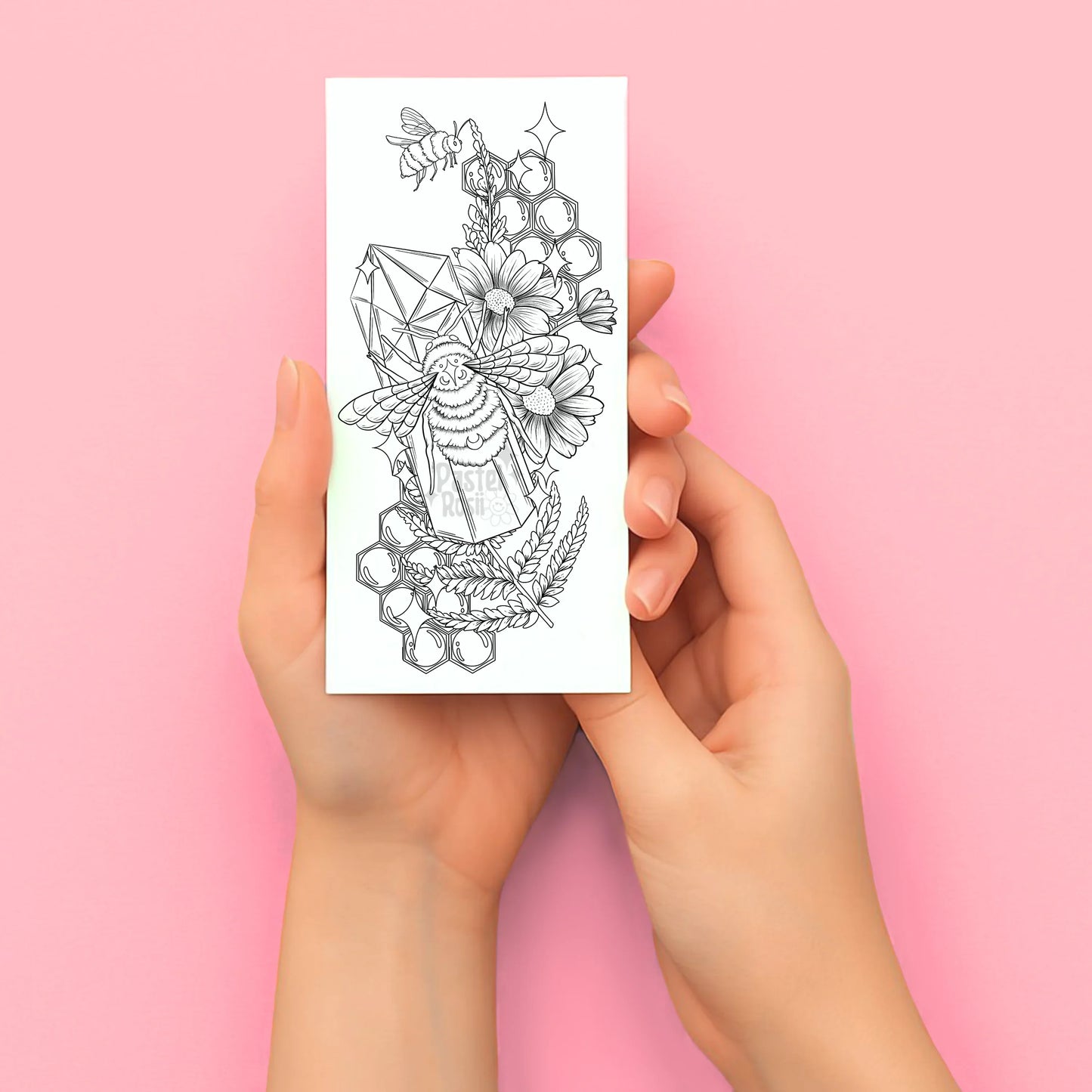 Hands holding a temporary tattoo with a geometric tattoo design on a pink background
