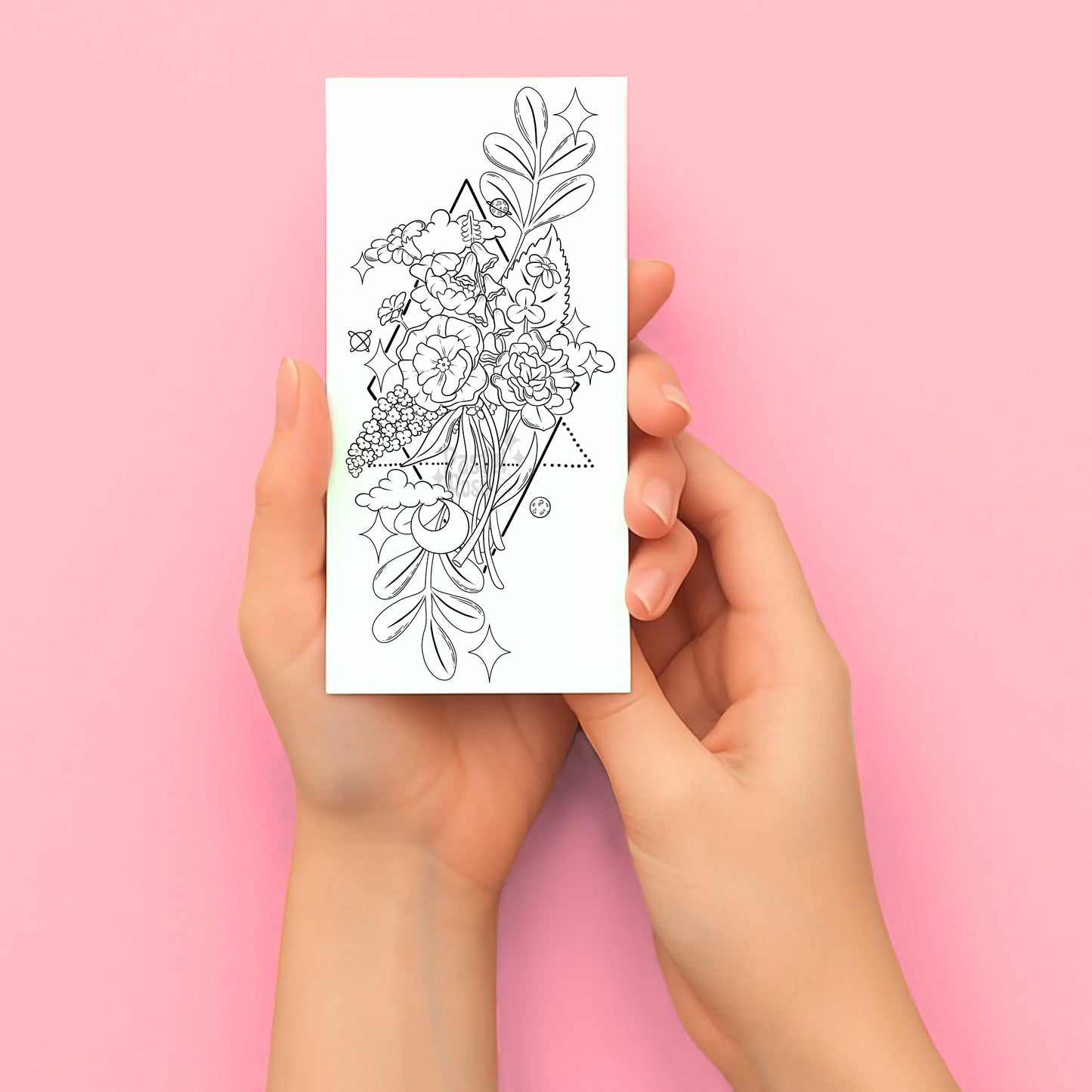 Hands holding a tattoo design sheet against a pink background