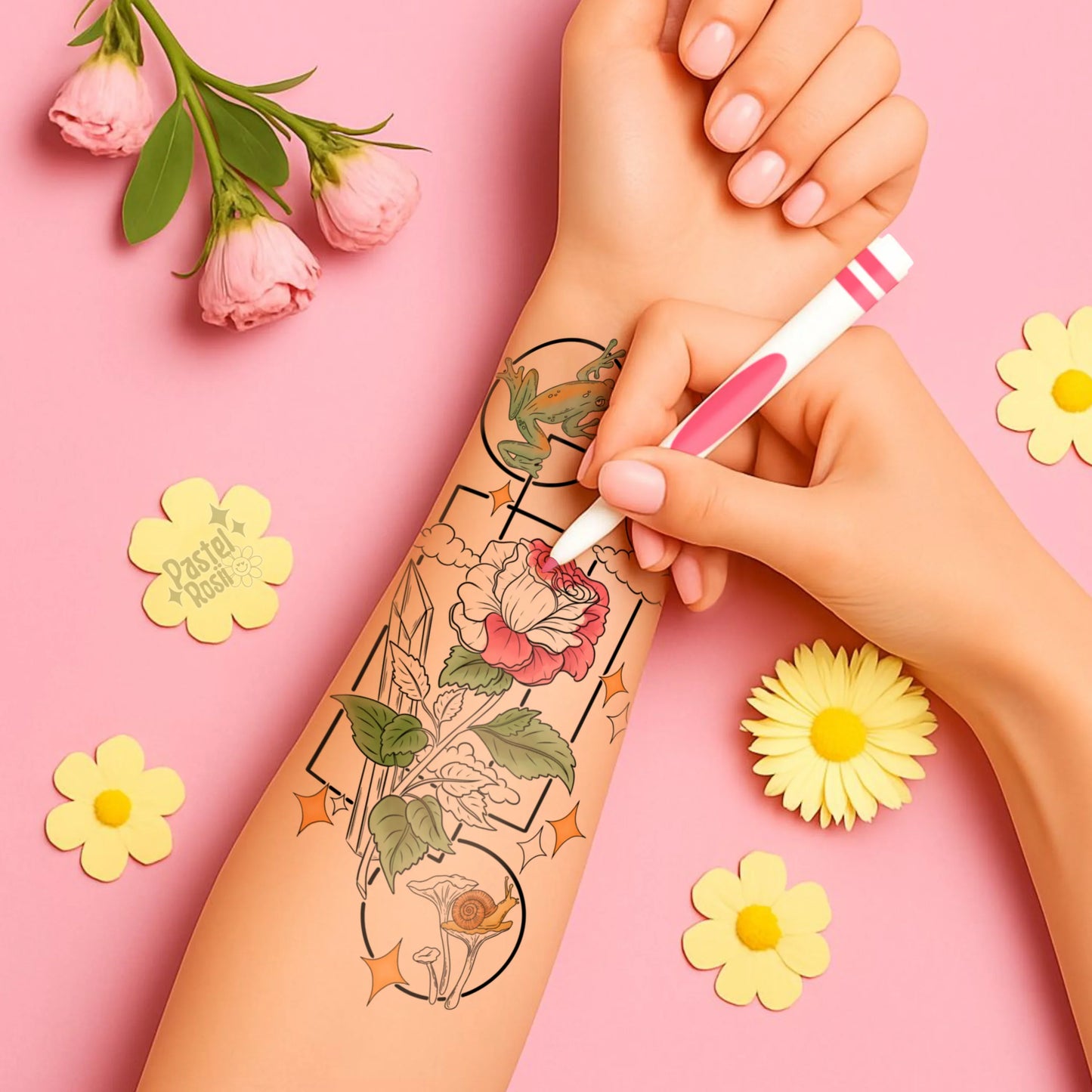 Person getting a floral tattoo on their arm with flowers and a pen in the background