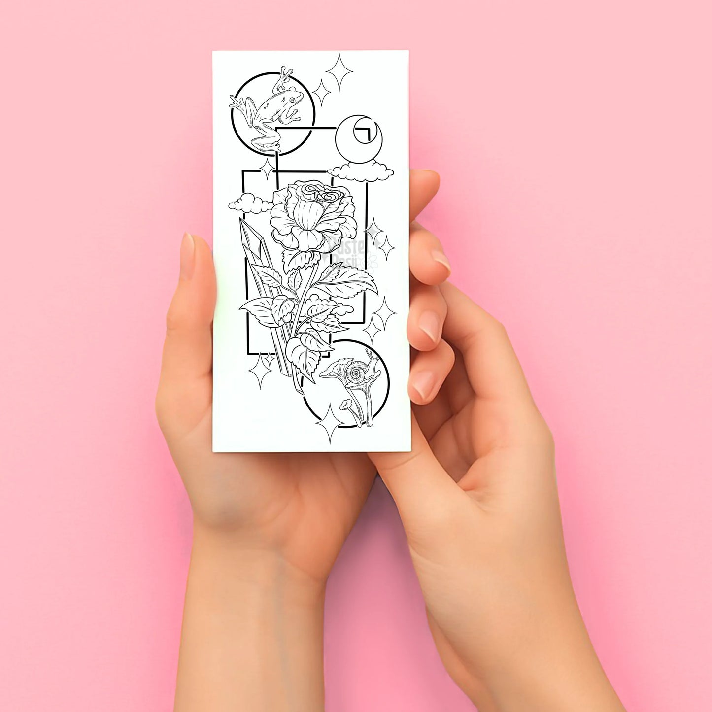 Hands holding a sheet of temporary tattoo designs on a pink background