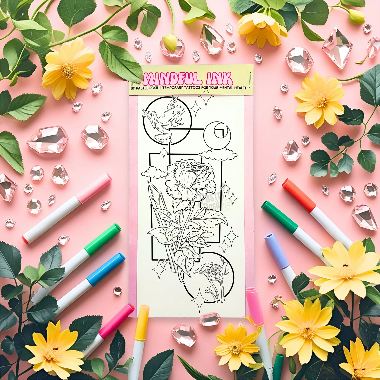 Mindul Ink tattoo design sheet surrounded by markers, flowers, and decorative elements on a pink background