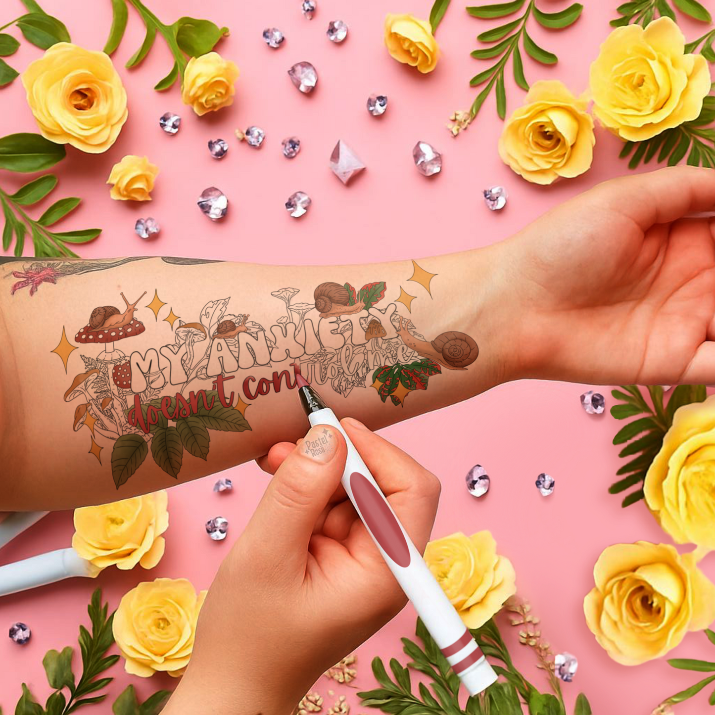 Tattoo on a person's arm with decorative elements like flowers and rhinestones on a pink background
