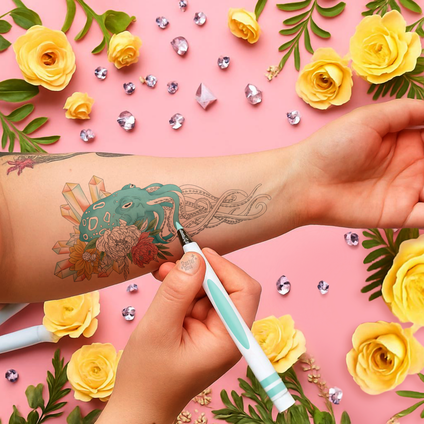 Person applying a temporary tattoo with yellow roses and decorative elements on a pink background
