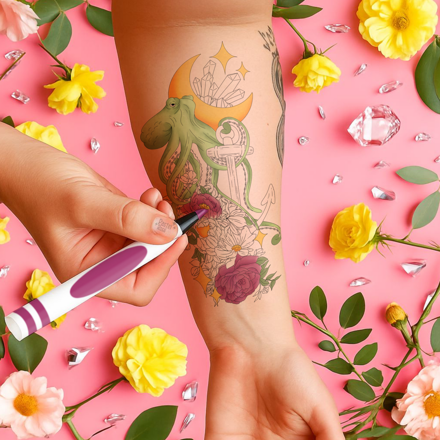 Tattoo artist applying a tattoo on a person's arm with flowers and crystals in the background