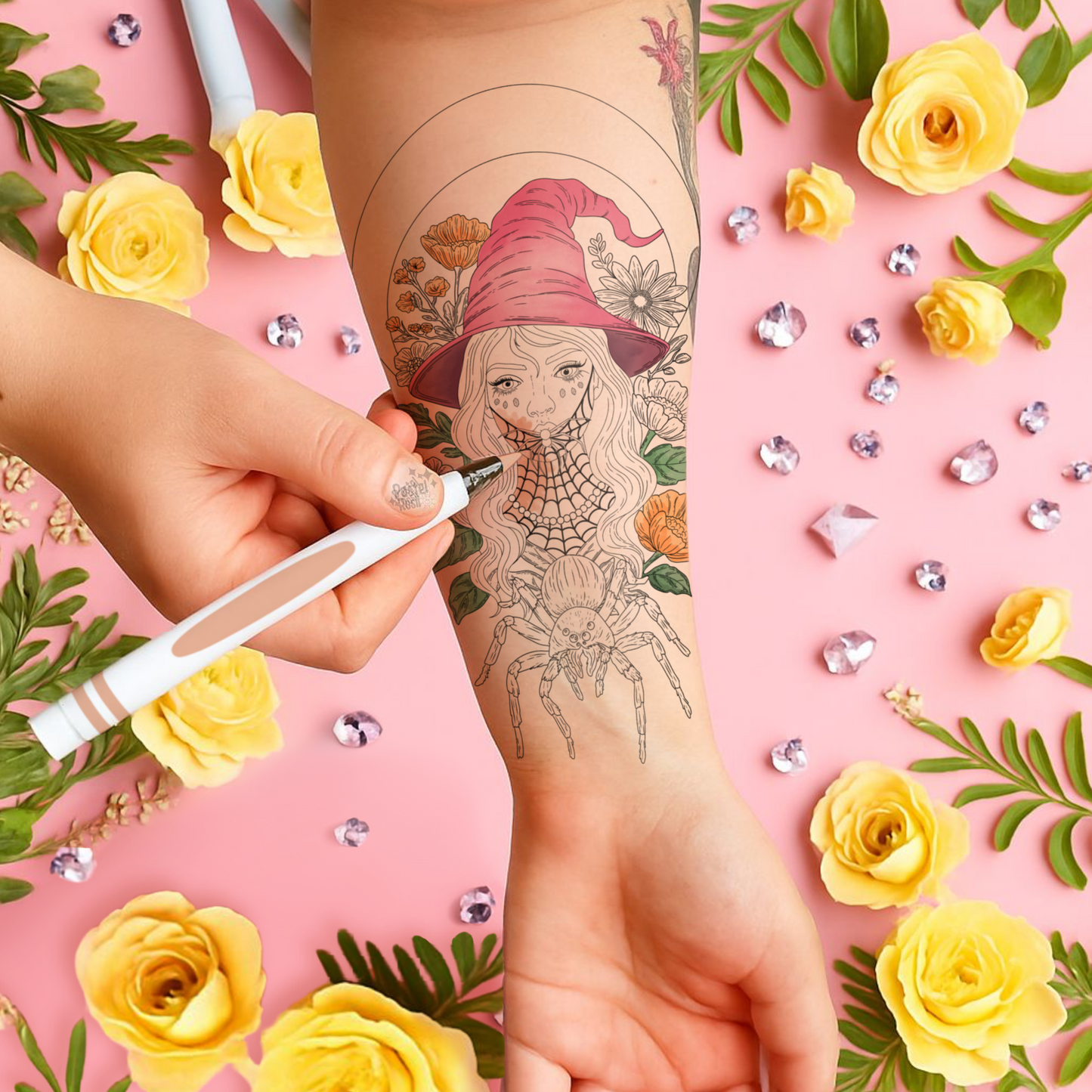 Tattoo artist applying a tattoo of a witch with a pink hat on a person's arm, surrounded by yellow roses and green leaves on a pink background.