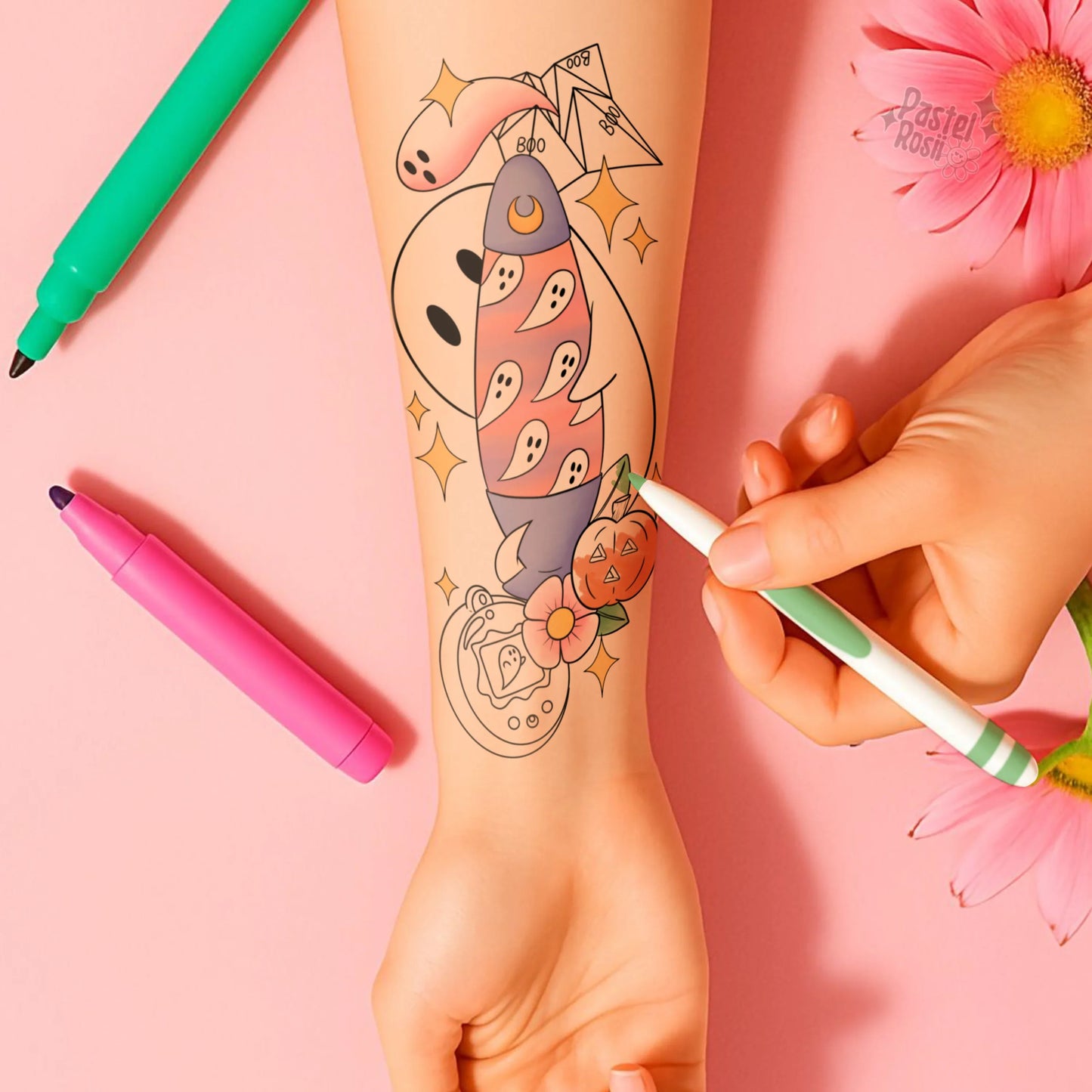 Person drawing a colorful tattoo design on their arm with markers, against a pink background.