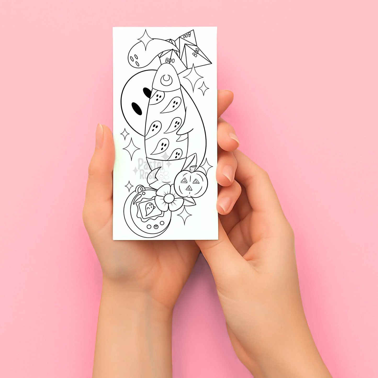 Hands holding a temporary tattoo with a Halloween-themed design on a pink background