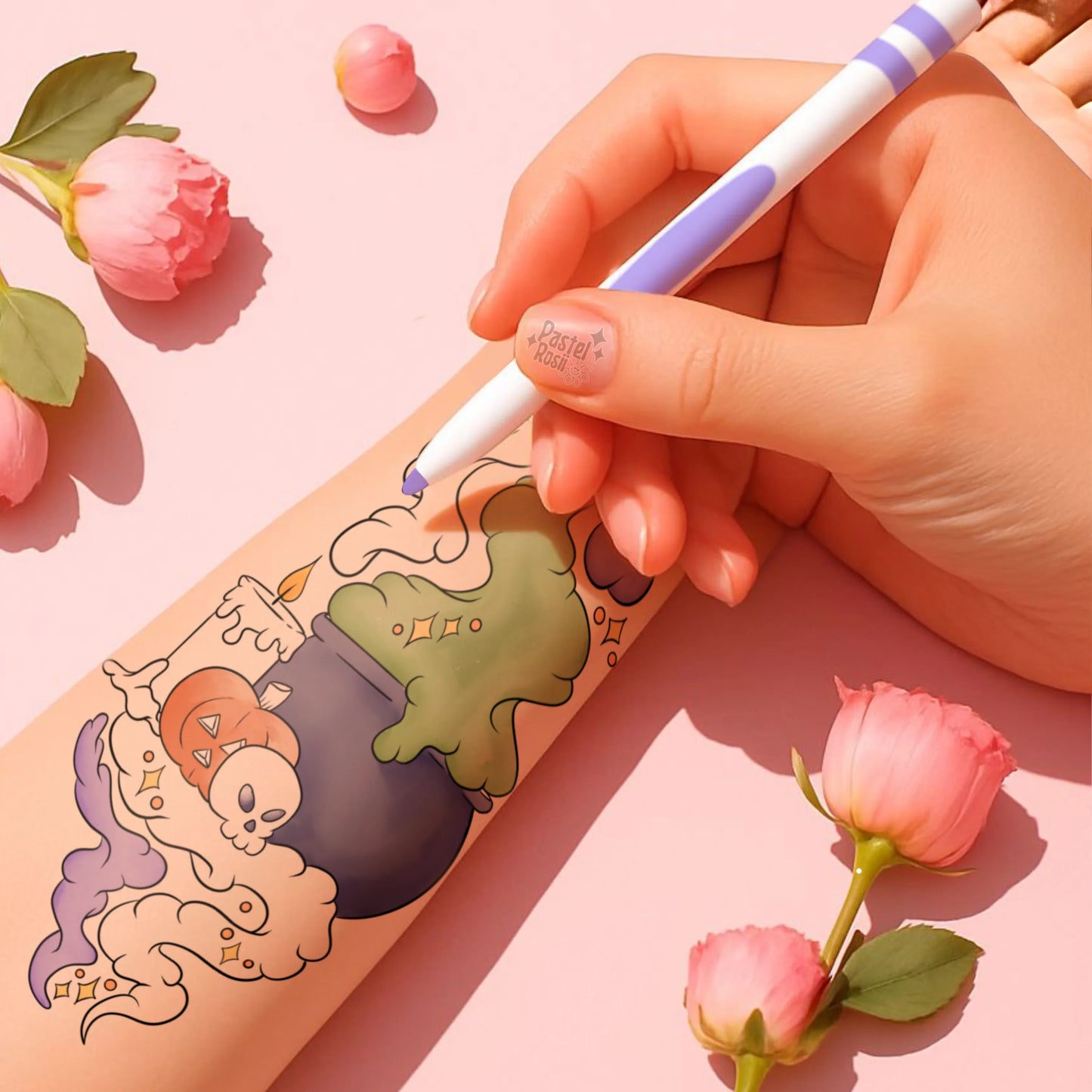 Hand holding a pen with a colorful design on a pink surface surrounded by flowers