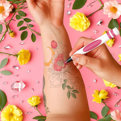 Hand applying temporary tattoo on arm with floral design, surrounded by flowers and crystals on pink background