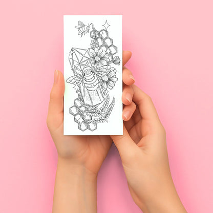 Hands holding a temporary tattoo with a geometric tattoo design on a pink background