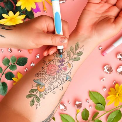 Hand applying temporary tattoo with floral design on arm against a pink background with flowers and rhinestones.