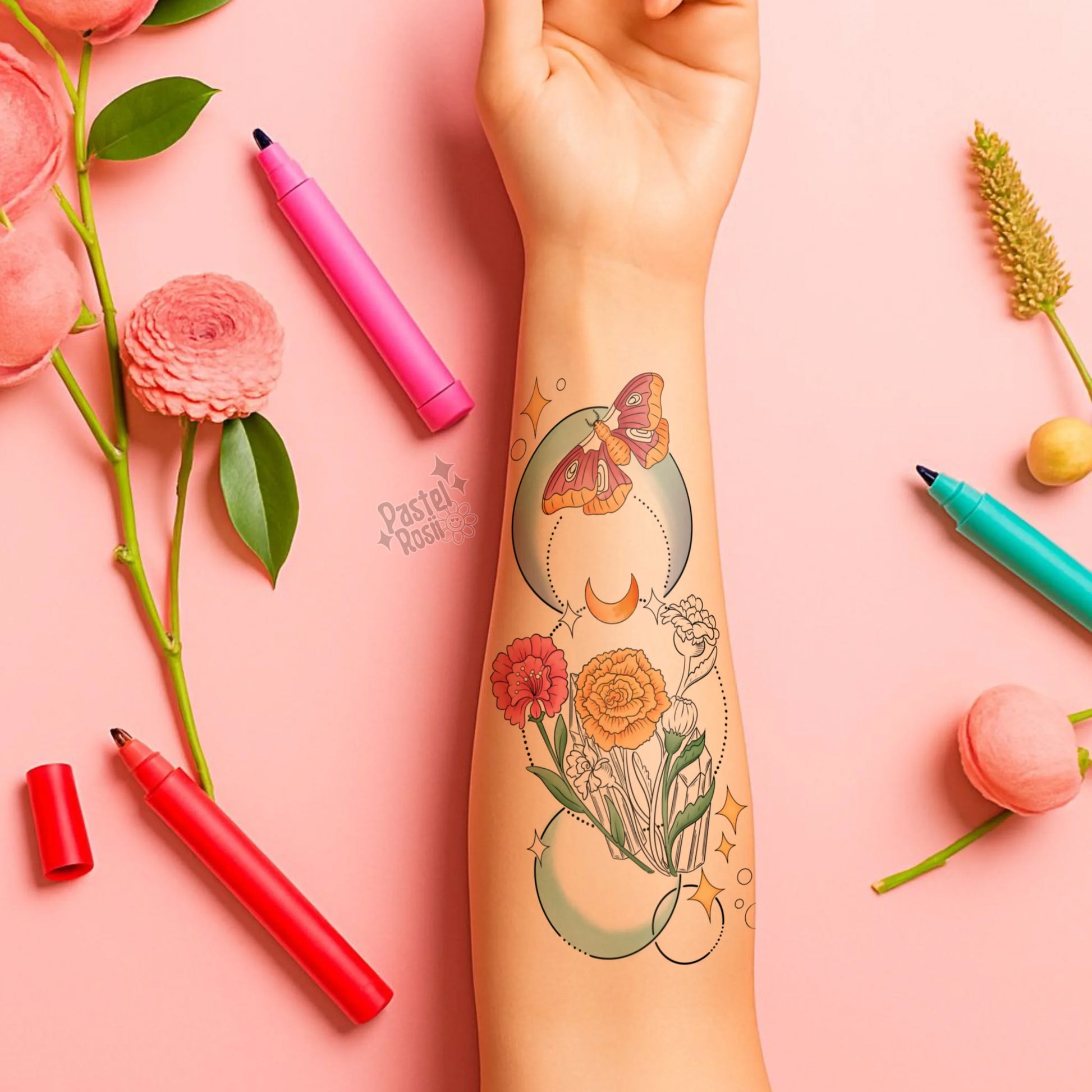 Tattoo of flowers and a butterfly on a person's arm with markers and flowers on a pink background