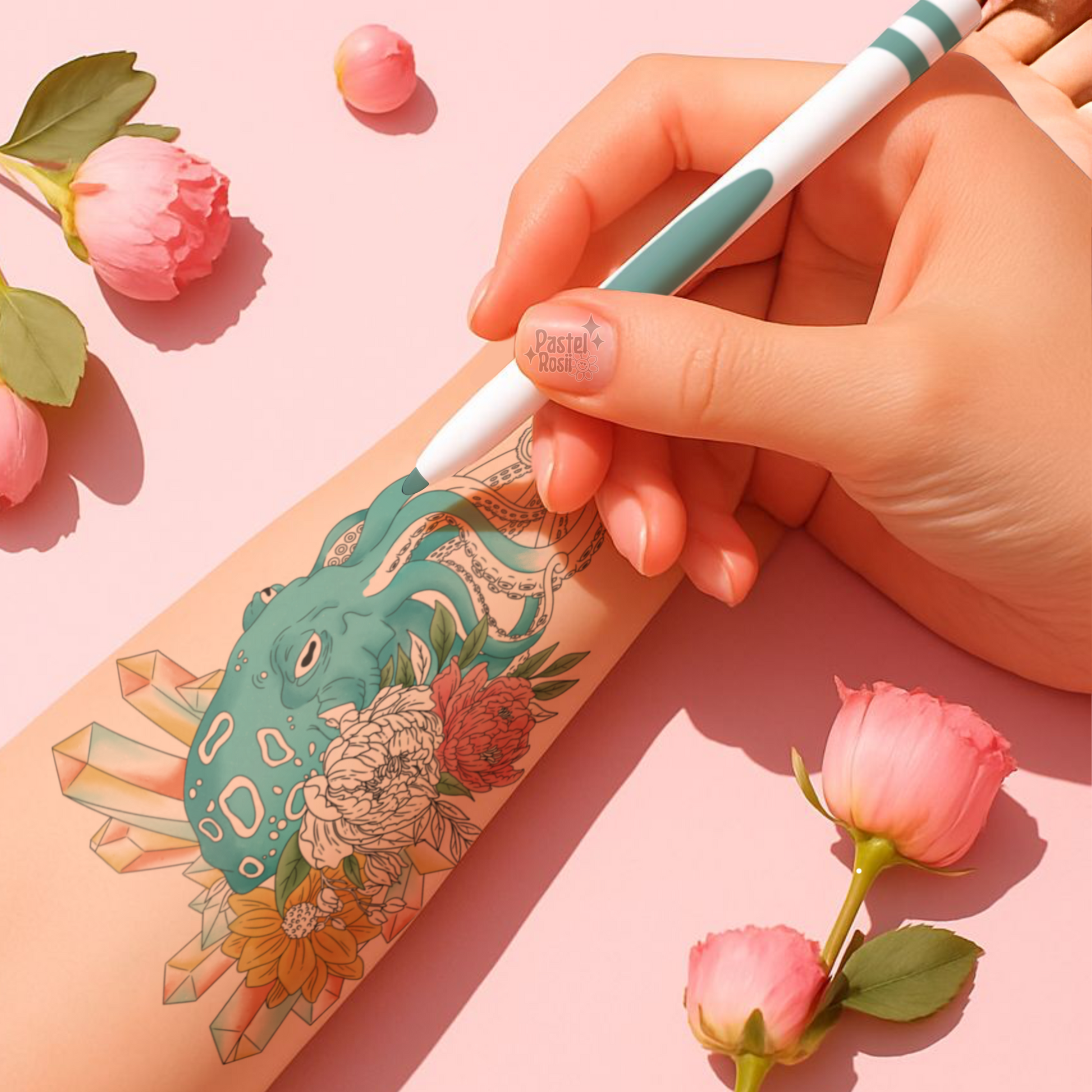 Hand holding a pen with a tattoo design on a pink background with flowers