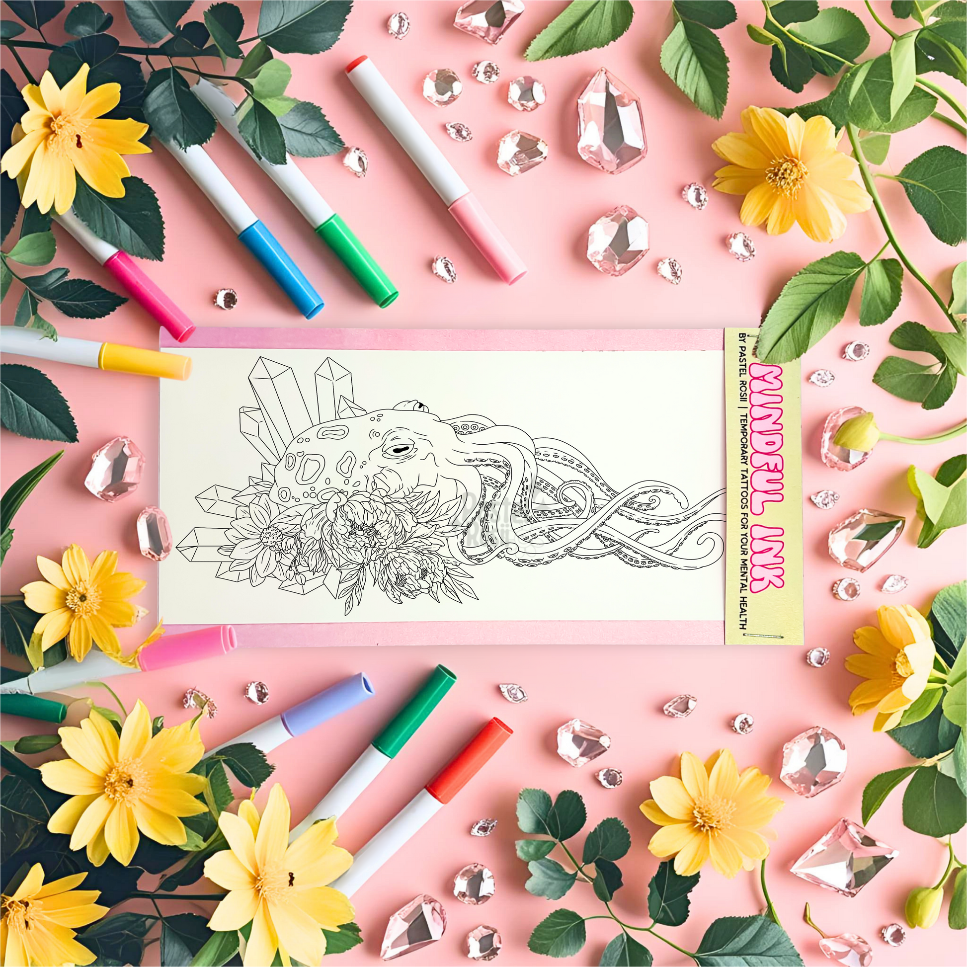 Temporary tattoo with octopus design surrounded by markers, flowers, and crystals on a pink background