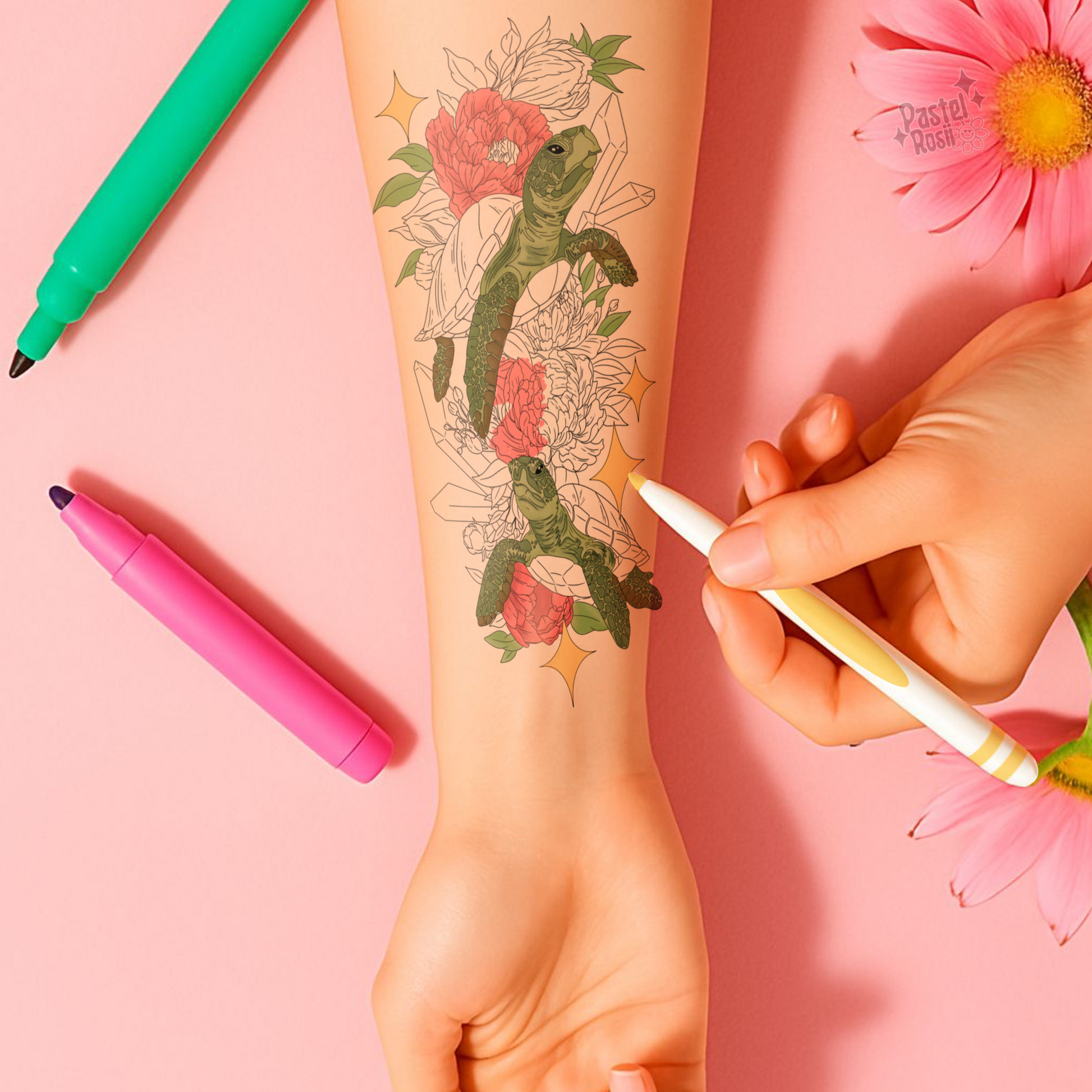 Tattoo of a turtle with flowers on a person's arm, with markers and flowers in the background.