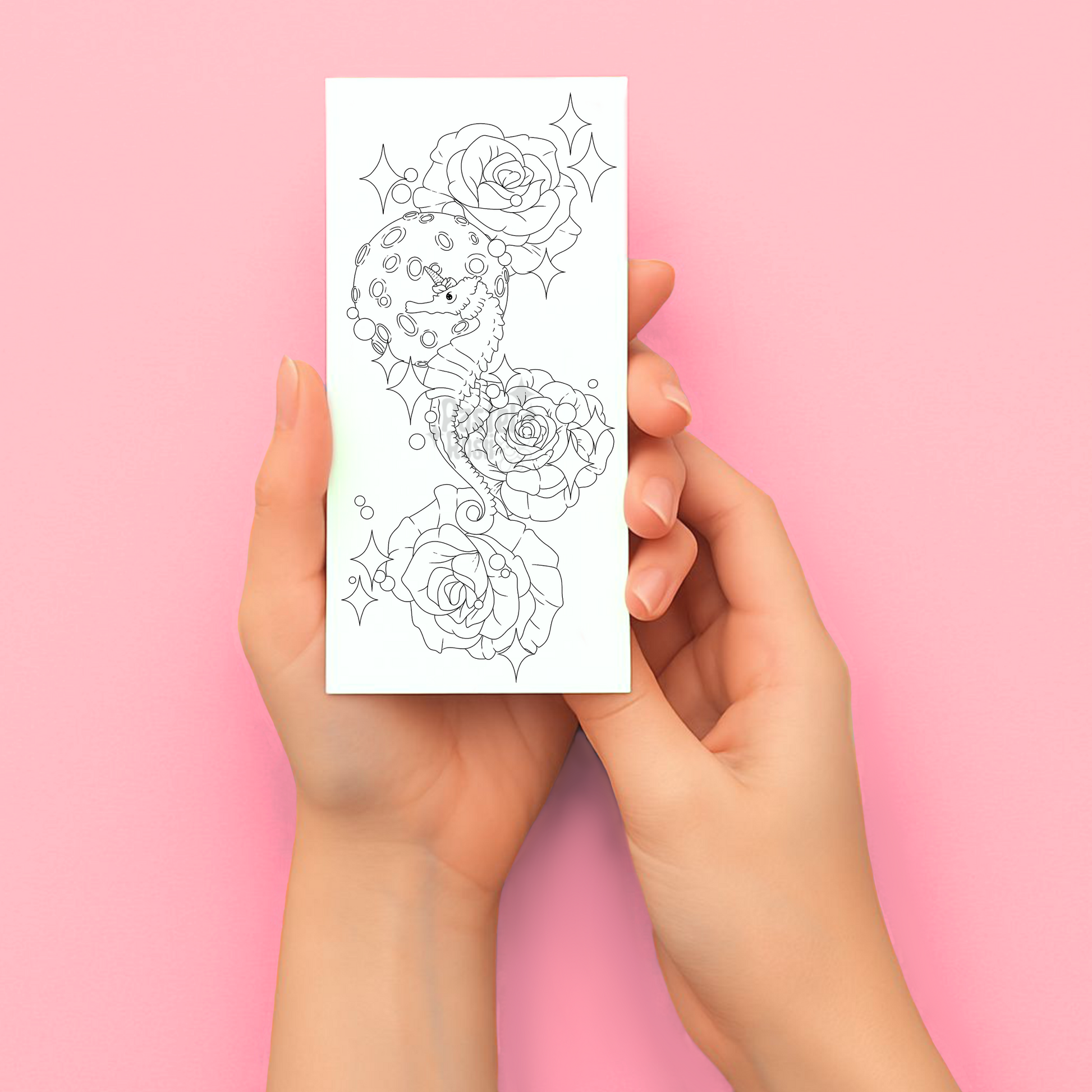 Hands holding a sheet of temporary tattoos with rose designs against a pink background